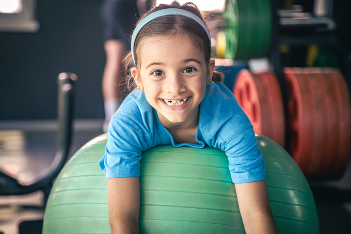 Happy girl stretches her body on a fitball in the gym.